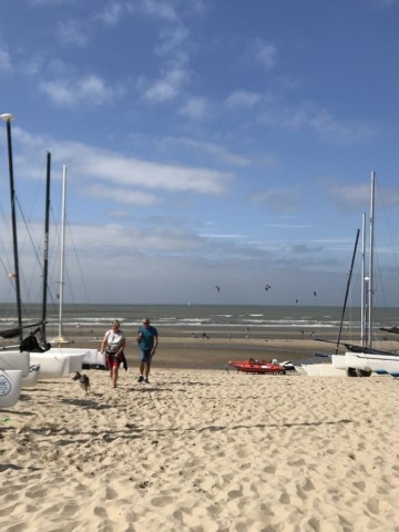 Boats line a sandy shore at the beach club in De Haan