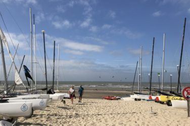 Boats line a sandy shore at the beach club in De Haan